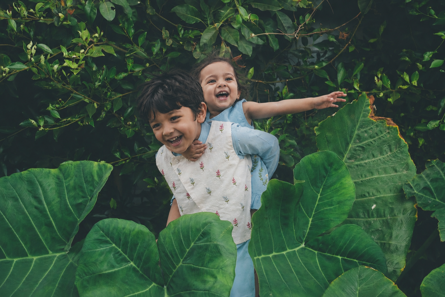 Child surrounded by green leaves